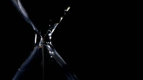 the sand flow in the hourglass with black background and lateral light backlight in lateral composition and possible endless loop