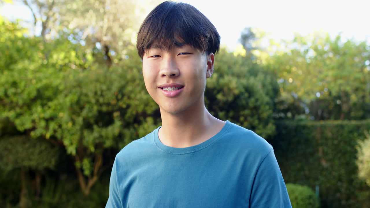 Smiling young Asian man enjoying outdoor time in garden, feeling happy and relaxed