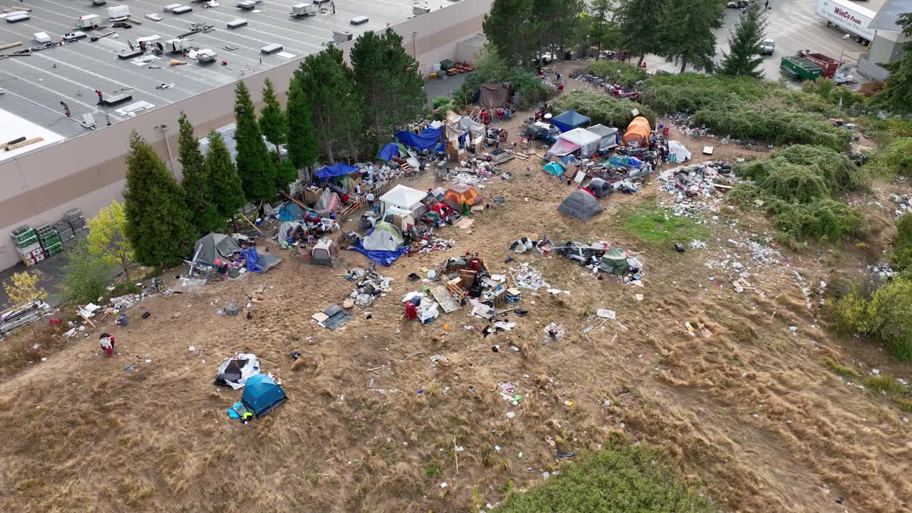 toma aérea de un campamento para personas sin hogar con carpas y basura esparcida por todas partes