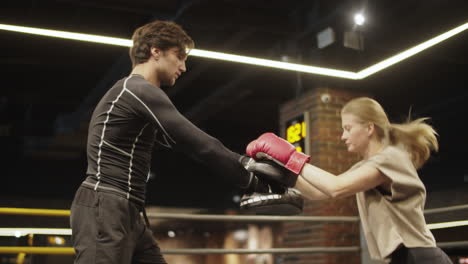 sport couple training on boxing ring. fit girl practicing leg hits in sport club