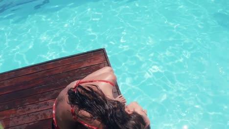 Attractive-brunette-sitting-by-the-pool-and-shaking-head
