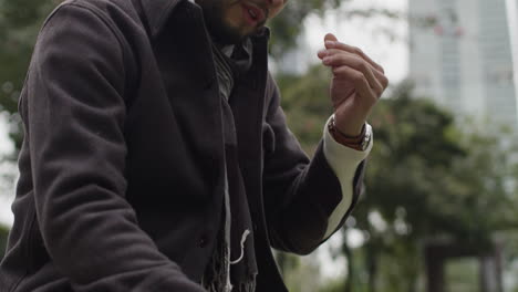 a sad, depressed and worried man sitting on a bench in a park alone, rubbing his forehead, stare lifelessly into the ground, submerged in thoughts