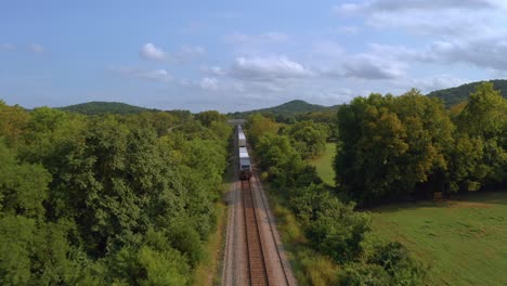 Drohne-Folgt-Einem-Zug-Auf-Den-Gleisen,-Während-Er-Durch-Einen-Baumtunnel-In-Einem-Vorort-Von-Tennessee-Rast