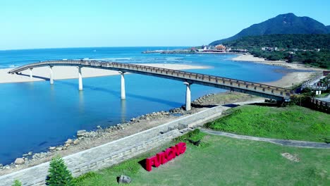 aerial shot of fulong water bridge with tropical landscape and mountains in background - taiwan,asia