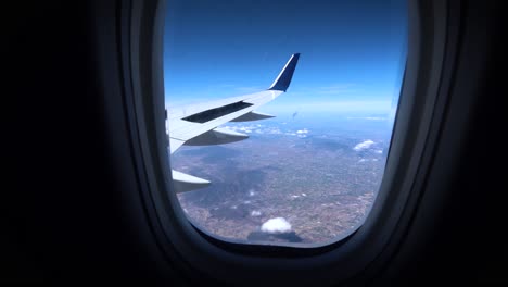 Travel-shot-outside-of-airplane-window,-looking-down-to-Mexico-landscape