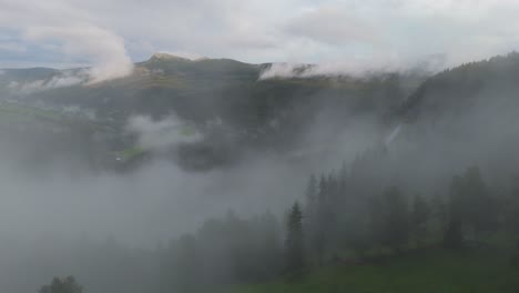 aerial view of foggy mountain landscape with lush green hills in the distance, partially obscured by mist, creating a peaceful and tranquil scene