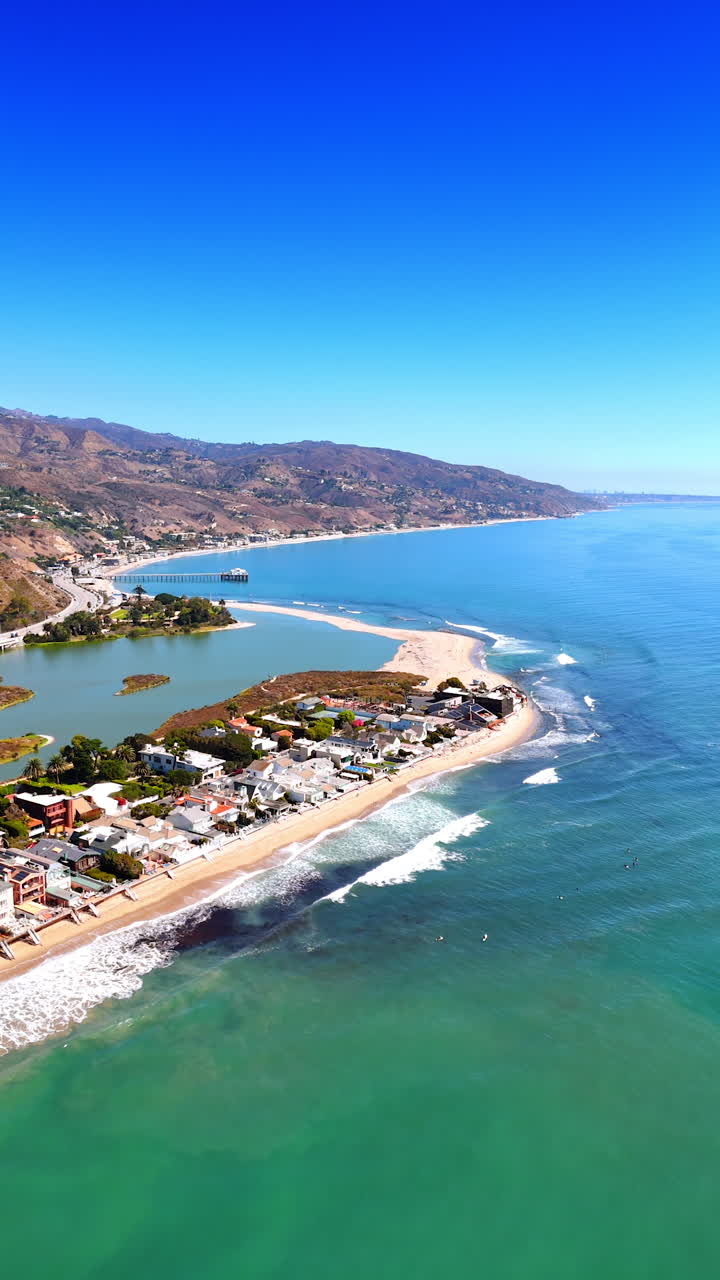 Acqua turchese dell'Oceano Pacifico con onde spumeggianti che si infrangono sulla spiaggia. Filmato con drone lungo la costa di Malibu, California, USA. Video verticale