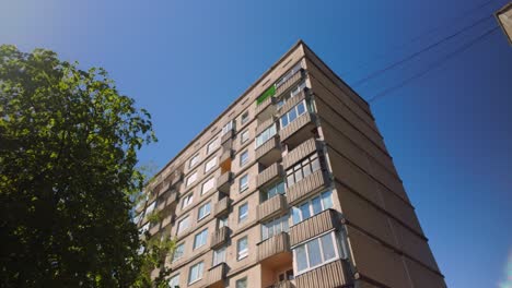 dreamy low angle wide pov of a soviet-era layered concrete apartment block with sunlight reflecting off its windows