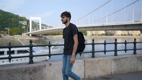 Junger-Reisender,-Der-Entlang-Der-Donau-In-Budapest-Mit-Elisabeth-brücke-Im-Hintergrund-Geht