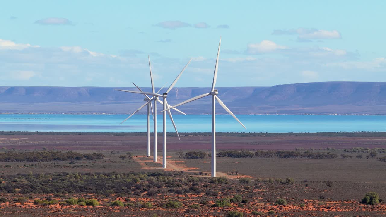 Aerial drone shot of wind farm with ocean and mountain ridge in South Australia