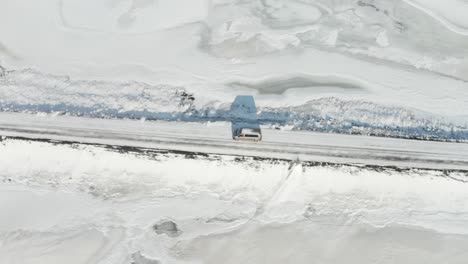 A-tracking-shot-for-a-gray-car-traveling-in-the-middle-of-the-snow