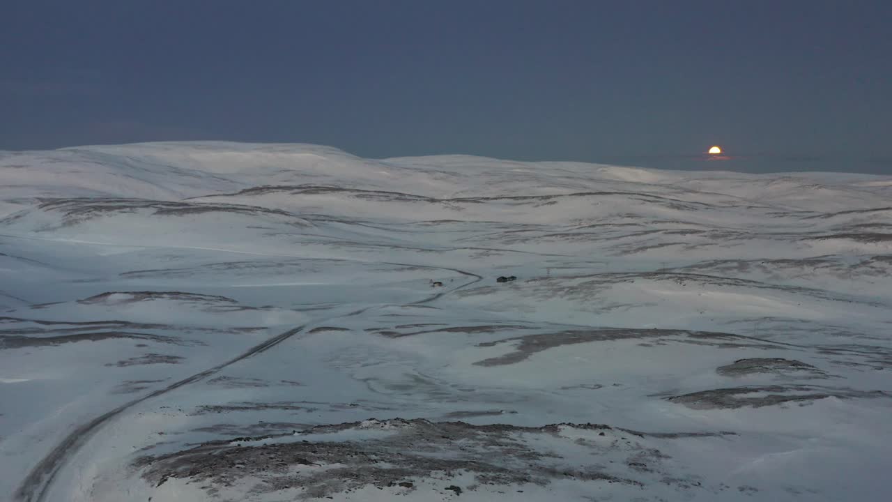 The road towards the most northern part of Europe, Nordkapp, during winter, with in the background a full moon. Aerial shot low to high.