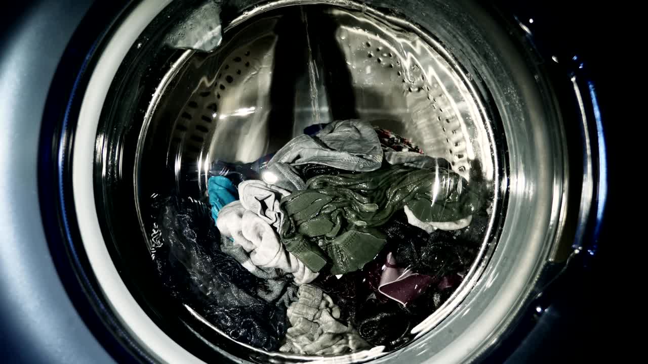 세탁기 문 안에는 회전하는 다채로운 옷이 있습니다.