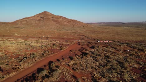 Aerial-establishing-shot-of-truck-driving-on-road-in-front-of-Mount-Bruce-in-desert-area