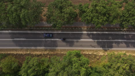 directly above drone pov of traffic on road through country landscape, aerial shot of many cars driving along the highway through nature on summer day