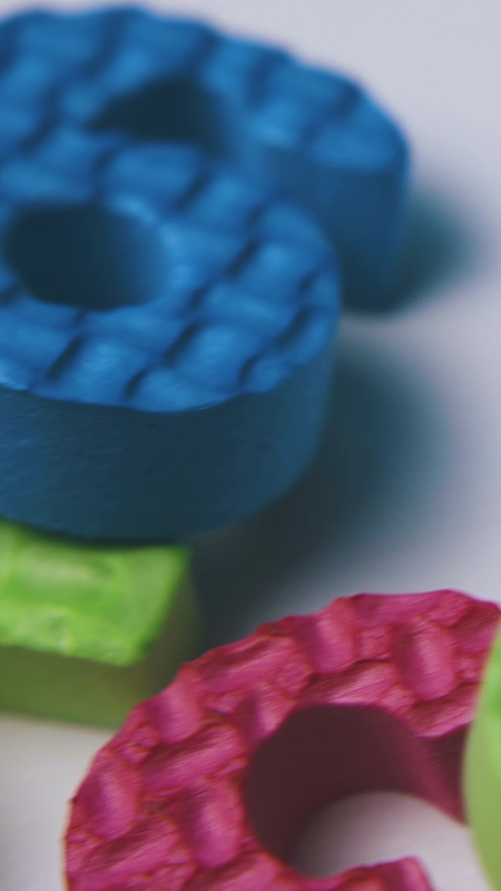 Pilha de diferentes números de borracha espuma coloridos, brilhantes e divertidos disposta sobre um fundo branco limpo, vista em close-up extremo