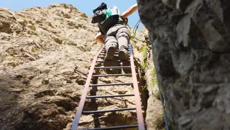person climbing a steep mountainside ladder