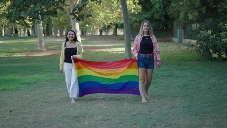 two women holding a pride flag in a park