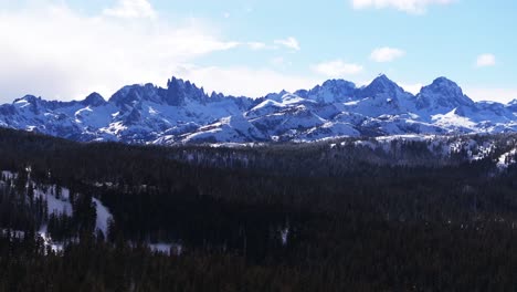 minarets jagged towering peaks summit vista panoramic landscape aerial drone winter mammoth mountain ski resort california inyo national forest the hemlocks sunny blue skies cloudy parallax right