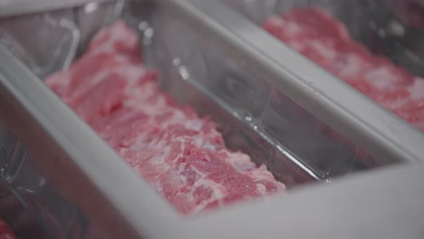 Fresh-ribs-getting-dropped-in-plastic-boxes-by-a-person