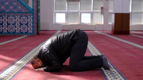 masked old man mosque kneels in prayer