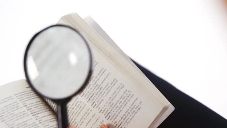 Businesswoman-looking-at-a-book-through-magnifying-glass