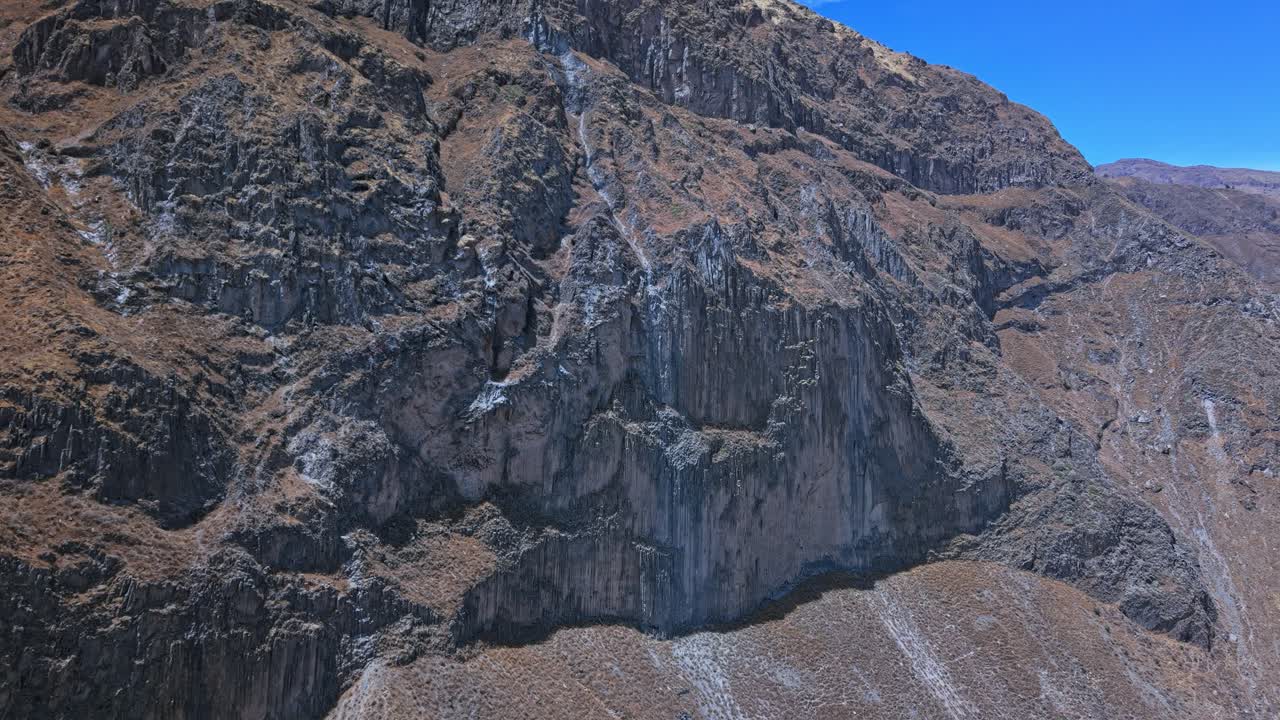 Drone approaches tallest sheer cliffs inside Colca Canyon Peru rising toward the canyon rim. Below, enormous piles of collapsed sediment reveal the scale of erosion and canyon’s raw geological power