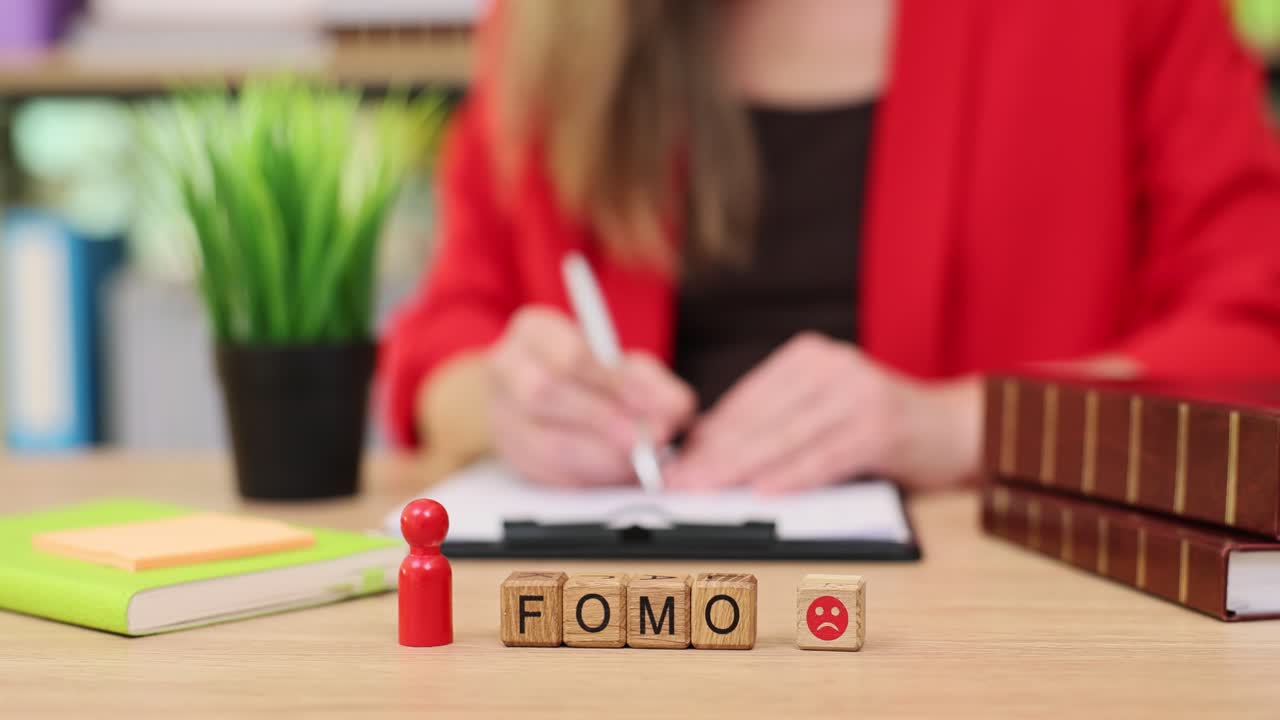 FOMO concept on a desk with a woman in the background