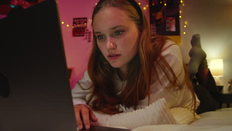 young woman using a laptop in her bedroom