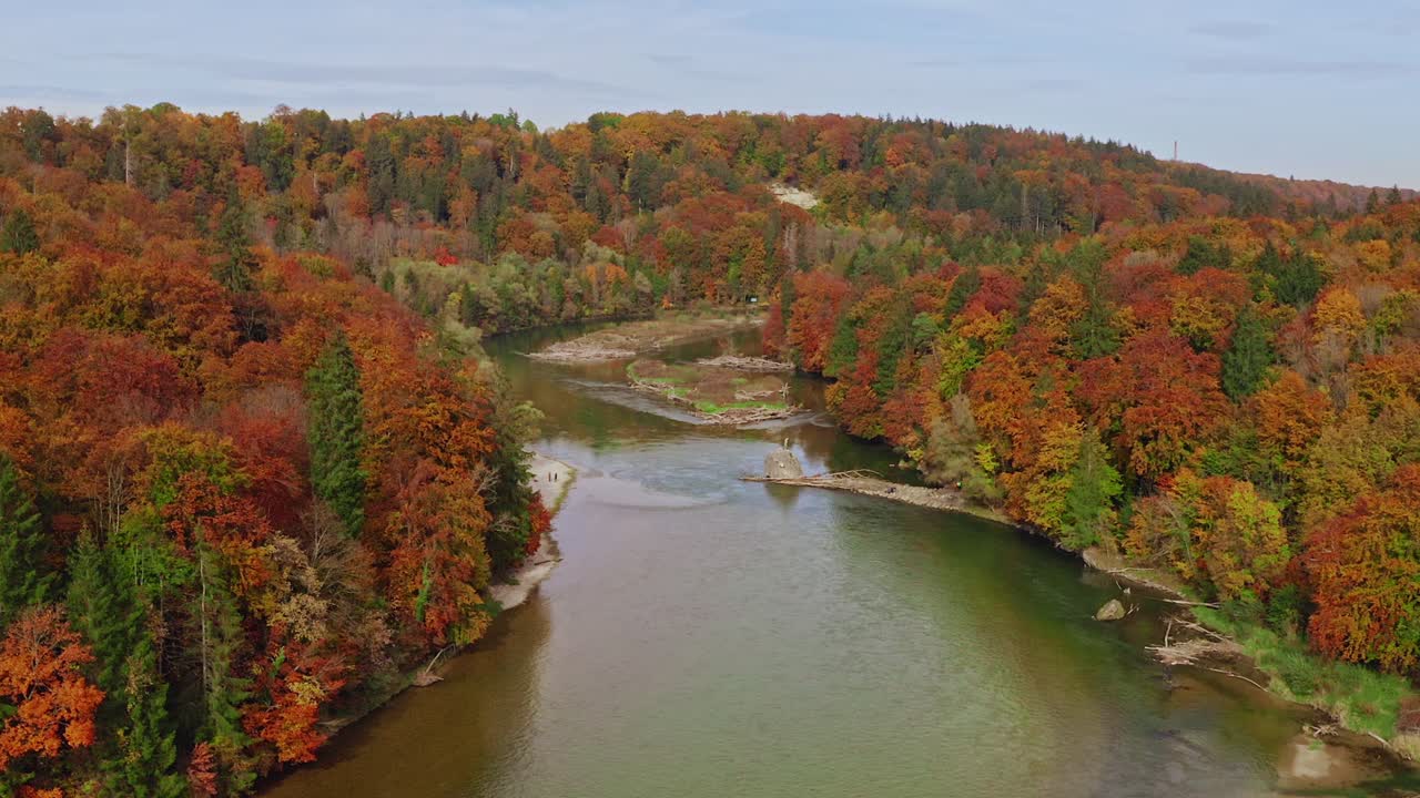 toma aérea de retroceso lento de un río que fluye a través de partes idílicas de color naranja, rojo y verde de un bosque