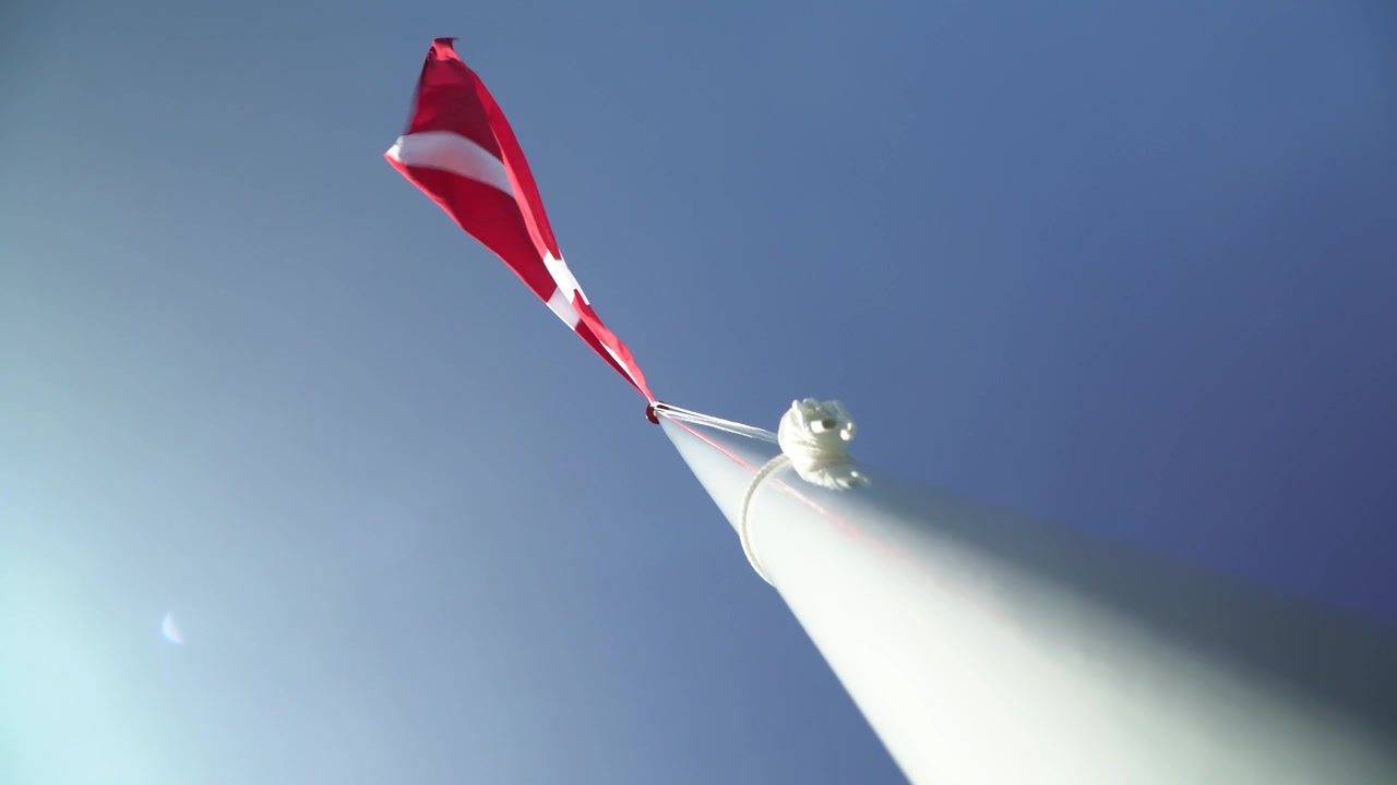 Danish Flag On Top Of Flag Pole Blowing In The Wind