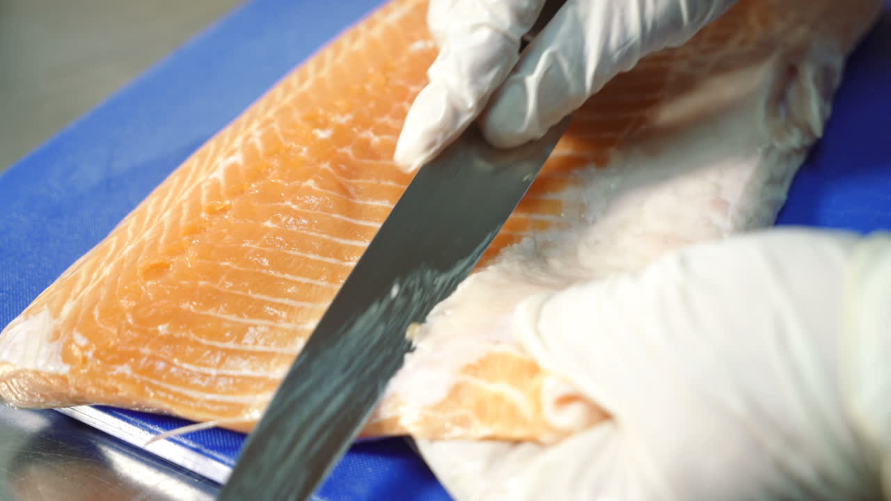 Cutting salmon with knife. Close up of cutting salmon filets in restaurant kitchen