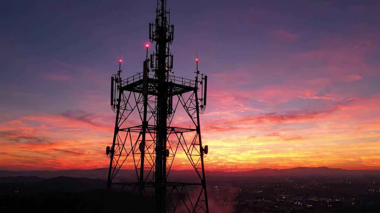 Uma Vista Deslumbrante do Pôr do Sol com uma Imponente Antena de Comunicação Silhuetada Contra um Céu Vibrante Cheio de Nuvens Coloridas e Tons de Crepúsculo.