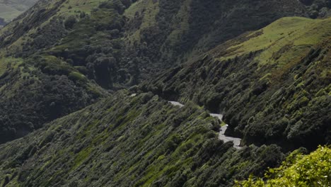coche conduciendo por una sinuosa carretera de montaña en la campiña costera de la isla norte de nueva zelanda