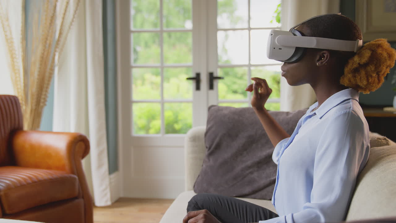 Woman Relaxing Sitting On Sofa At Home Wearing VR Headset And Interacting With AR Technology