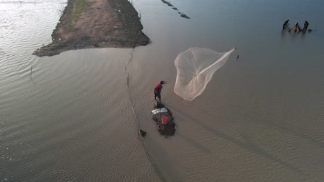 fisherman cast net fishing in tonle sap waterway in asia, aerial birds eye view during late afternoon setting sun, slow-mo static