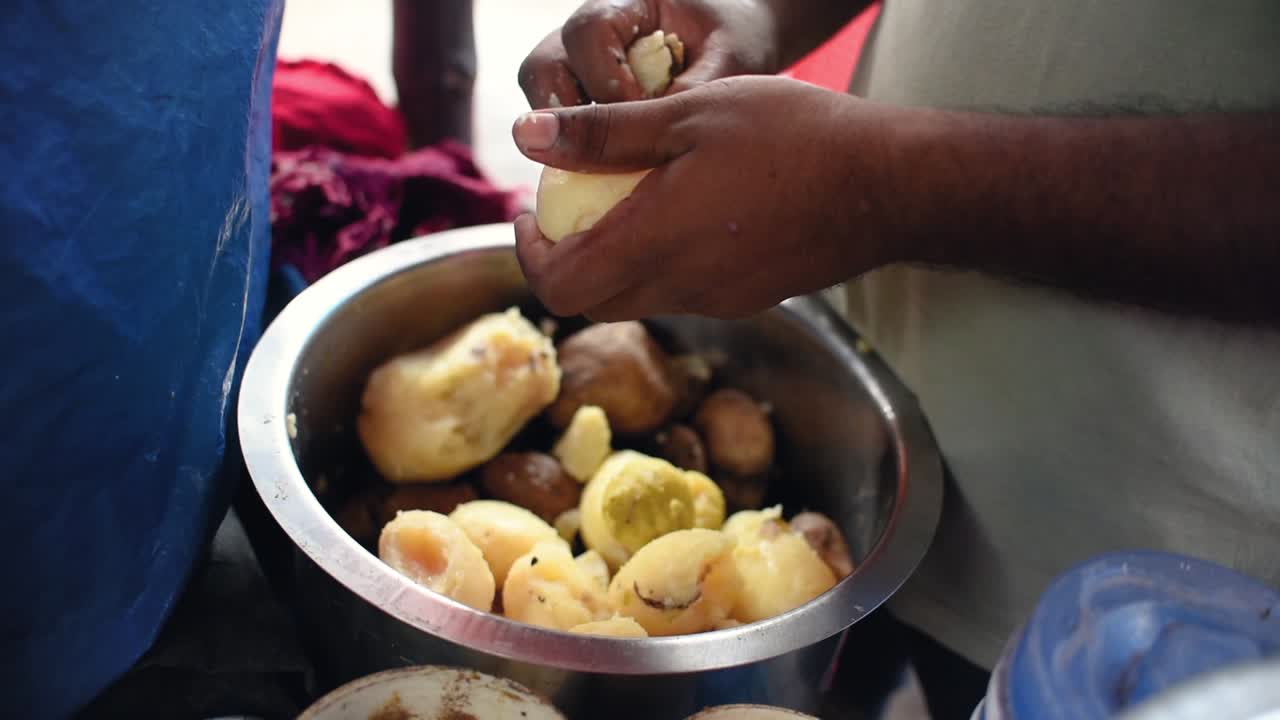 un hombre irreconocible pelando papas en un puesto de comida callejera en india, asia, cámara lenta, cerrar