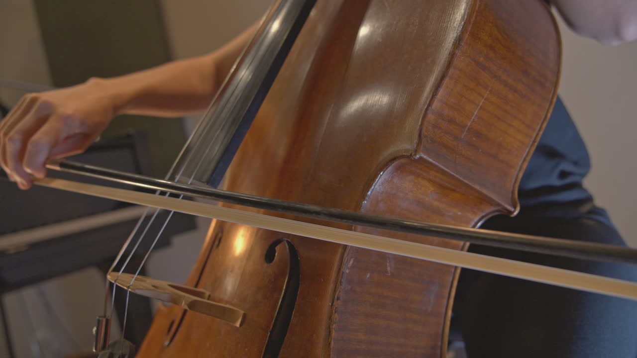 Primo piano di un musicista che suona un violoncello con un archetto