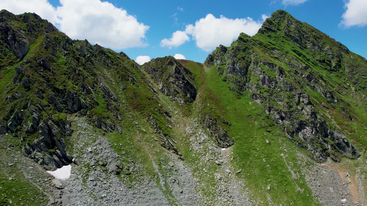 vista aérea de una hermosa cadena montañosa con picos altos, nubes gruesas y esponjosas y un hermoso valle verde, montañas de los cárpatos, carretera transfagarasan transilvania, rumania