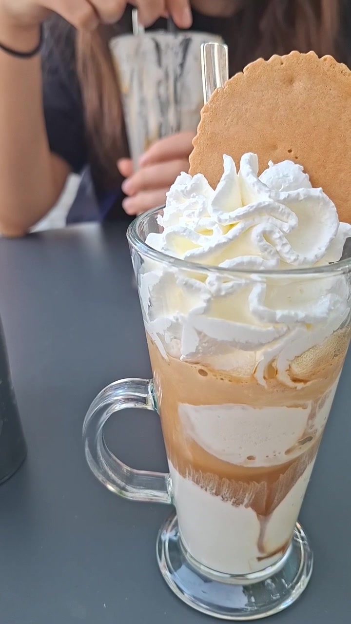 Postre de café estilo affogato en vaso con chica borrosa comiendo postre de fondo, vertical
