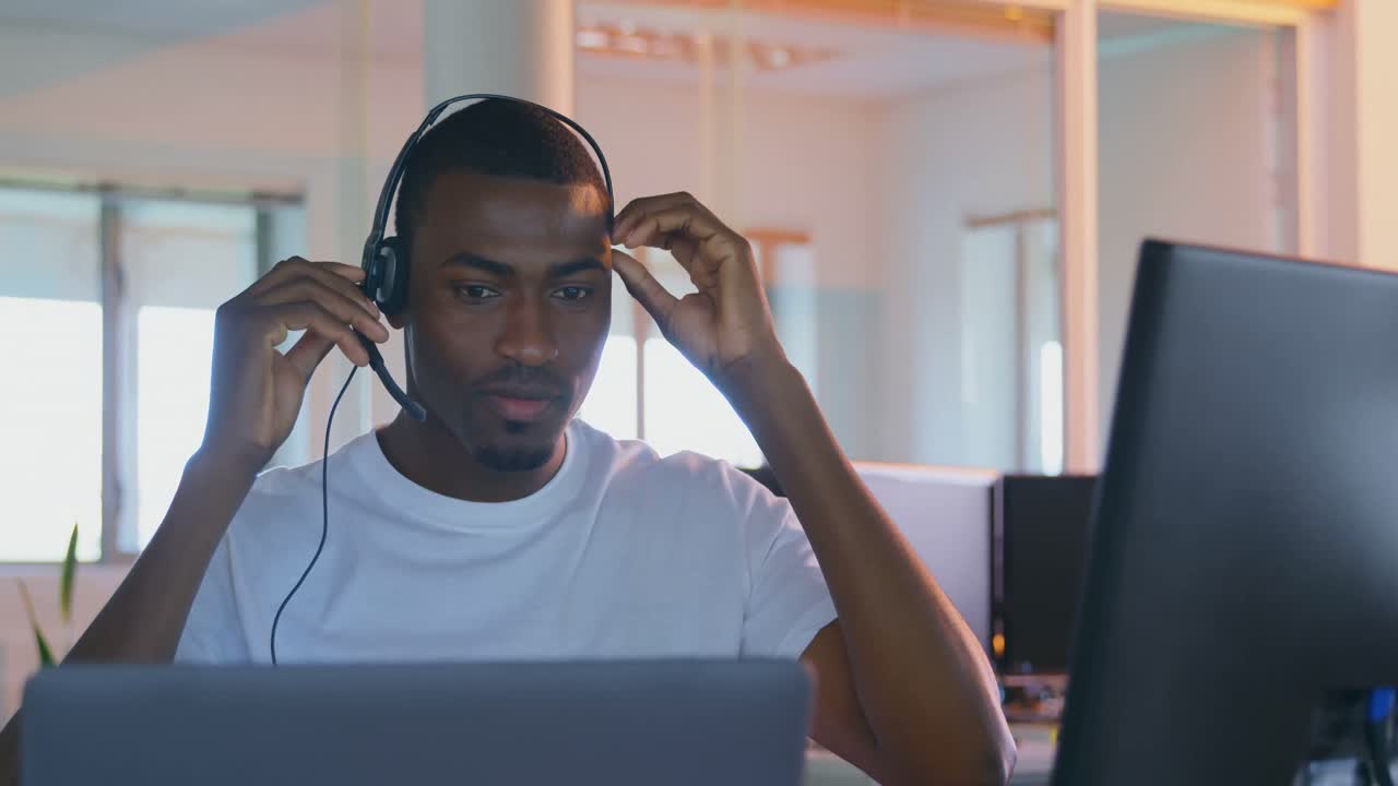 Front view of young black male executive working on computer at desk in modern office 4k