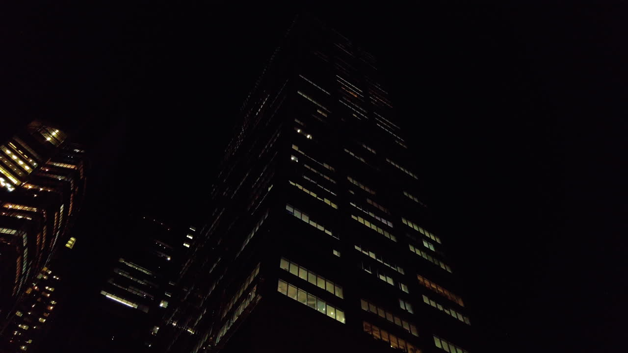 Looking up at skyscraper with lights on at night in downtown Sydney, slow motion