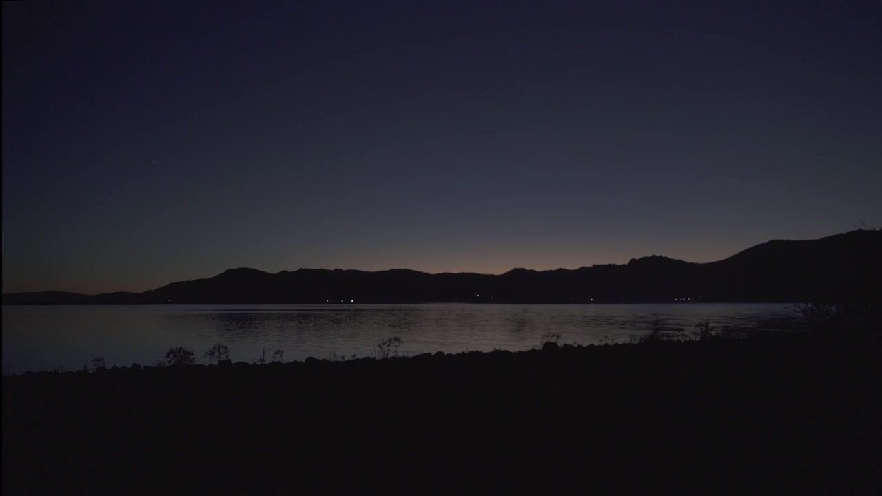 Veduta serena al tramonto su un lago tranquillo e montagne in lontananza