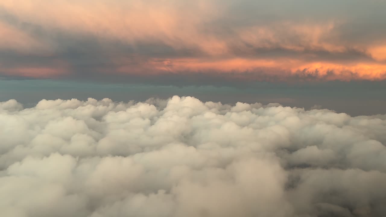 A pilot’s FPV flying among layers of clouds with the early morning light with come clouds illuminated by the sunrise. Aerial shot from a jet cockpit. 4K 60FPS