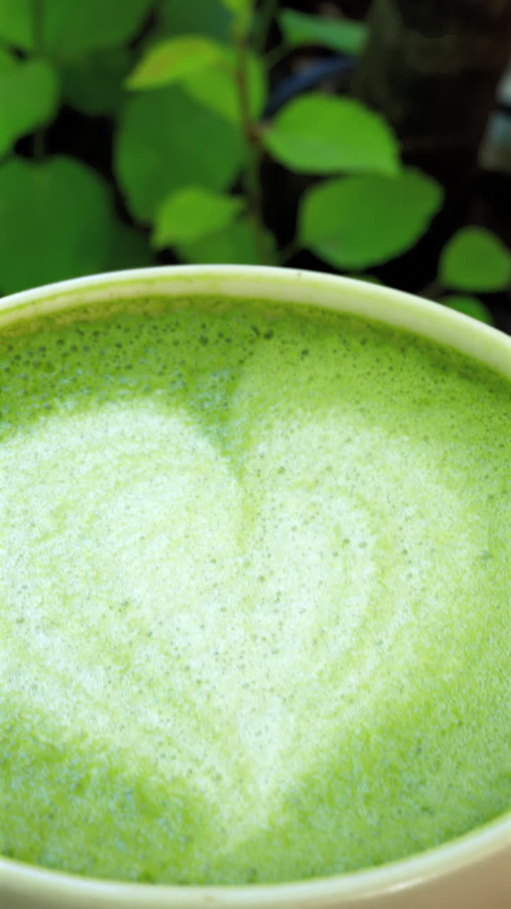 Close up of a heart latte art on a matcha latte. Vertical