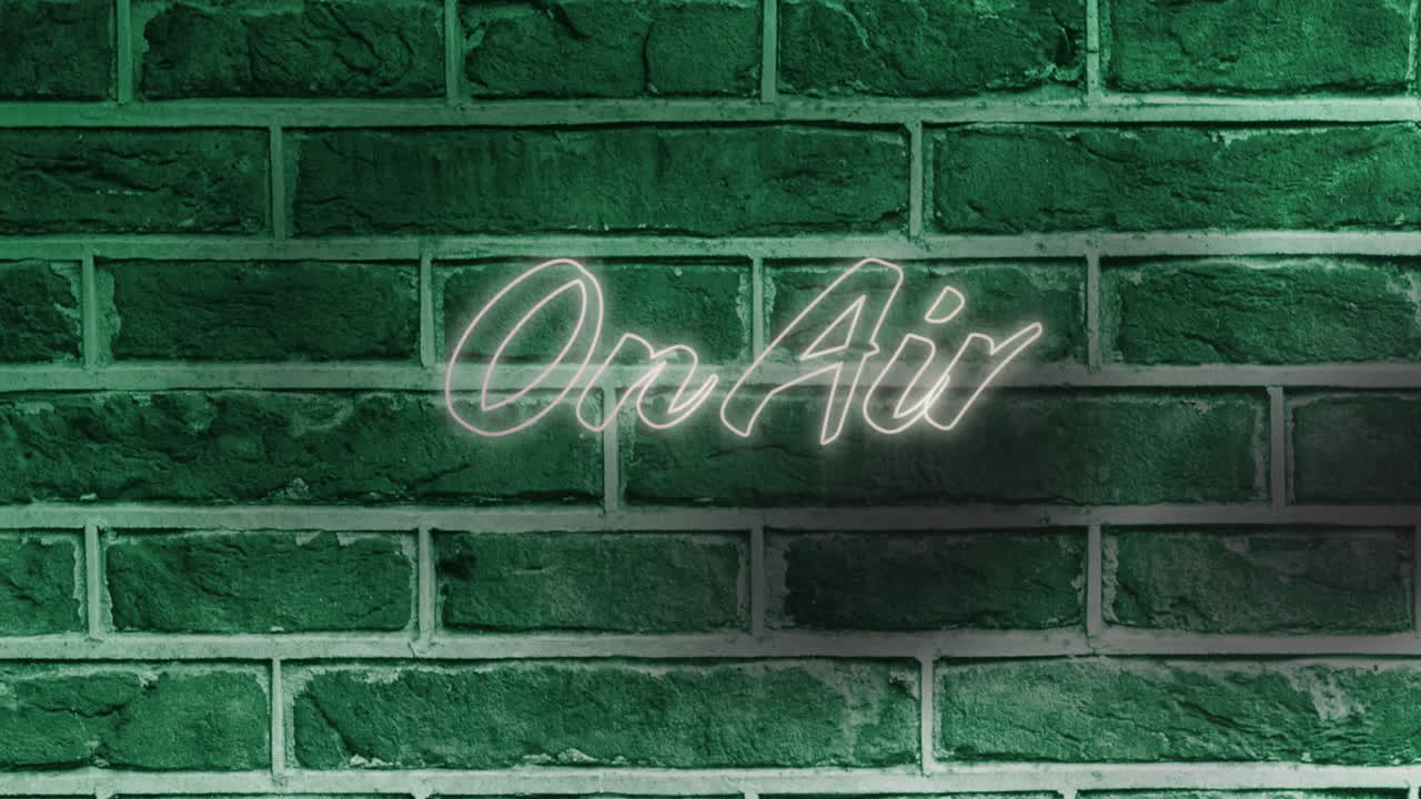 Neon on air text against green brick wall in background