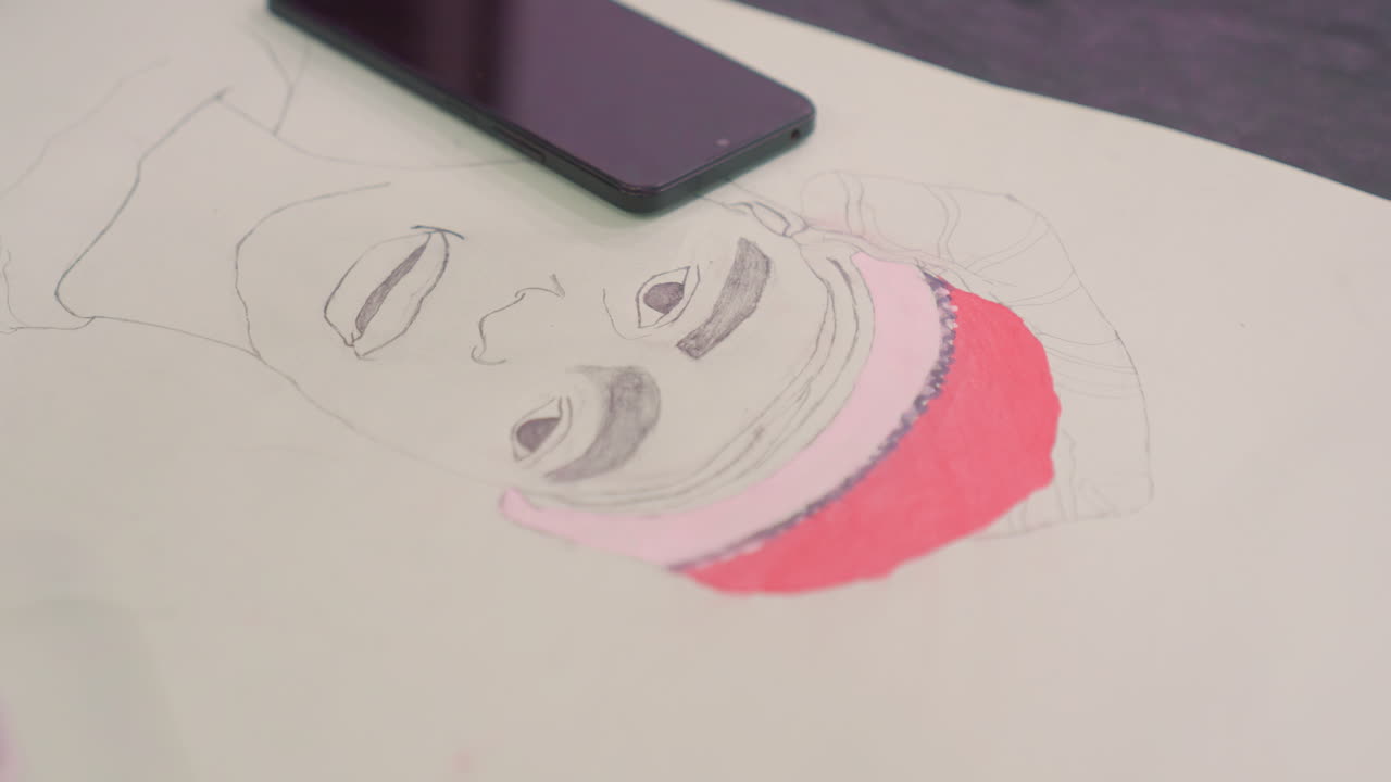 Boceto de retrato aéreo con teléfono sobre papel, contornos negros y sombrero rosa parcialmente coloreado, smartphone apoyado en la hoja, momento de estudio tranquilo, composición minimalista e iluminación suave, listo para documentar.