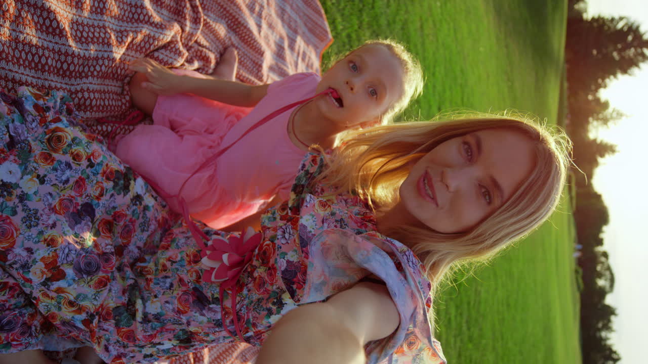 Schöne Frau umarmt Tochter im Stadtpark. Fröhliche Dame schickt draußen einen Kuss.