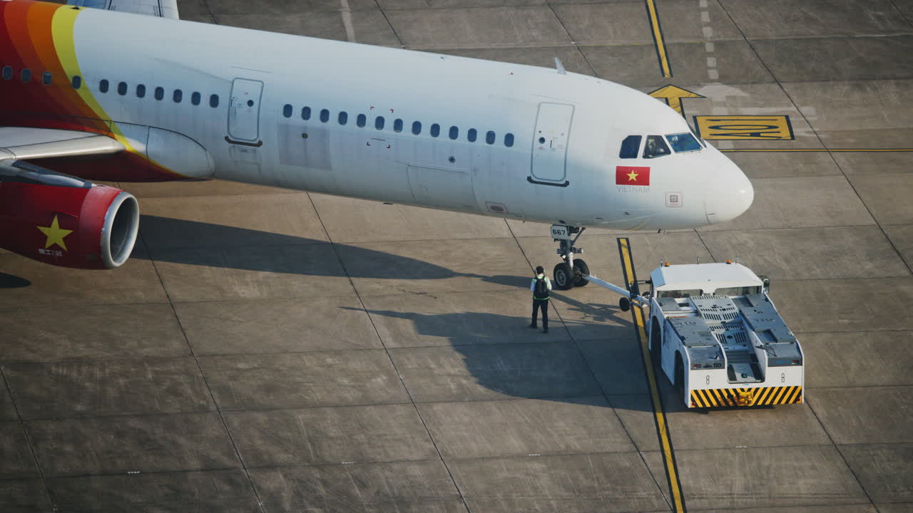 Personale di terra che effettua il pushback di un aereo commerciale sul piazzale dell'aeroporto