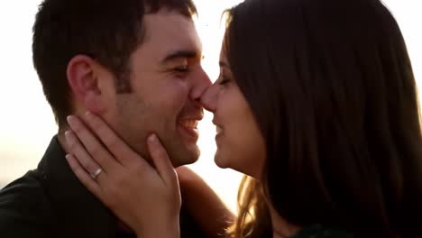 a heartwarming moment of connection: a couple sharing joyful intimacy as their faces touch and smiles illuminate the sunset background in a tender embrace